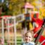 Enfant utilisant le Safety Seat Single Swing dans une aire de jeux.