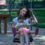 Mère et enfant assis ensemble sur Safety Seat Single Swing dans une aire de jeux.