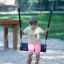 Enfant assis sur Safety Seat Single Swing dans une aire de jeux
