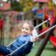 Enfant sur Safety Seat Single Swing dans une aire de jeux.