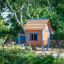 Une maison de jeu en bois colorée nommée Olle's Playhouse dans un parc.