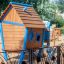 Structure de jeu en bois Olle's Playhouse avec des accents bleus dans une aire de jeux