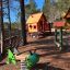 Olle's Playhouse : Maison de jeu en bois avec toboggan et ressort vert dans une aire de jeux sur le thème de la forêt.