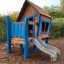 Maison de jeu en bois Olle's Playhouse avec un toboggan pour enfants dans un parc.