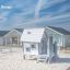 Olle's Playhouse dans une aire de jeux sablonneuse avec des maisons modernes en arrière-plan.