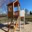 Maison de jeu en bois avec échelle et toboggan dans une aire de jeux extérieure