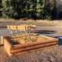 Sandbox en bois naturel avec bancs en arrière-plan, conçu pour les aires de jeux extérieures.