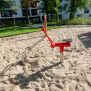 Excavator rouge pour enfants sur aire de jeux en sable, conçu pour creuser et manipuler facilement.
