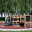 Structure de terrain de jeu Blackboard 156 cm avec toboggan et éléments d’escalade dans un parc.