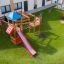 Aire de jeux extérieure avec un toboggan rouge et une structure d’escalade pour enfants.