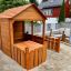 Wooden Garden Playhouse w/ Fencing dans un jardin arrière.