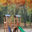 Ensemble de jeux d’extérieur en bois Mini Play Modern Nature avec toboggan dans une forêt d’automne.