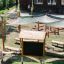 Salle de classe extérieure avec bancs en bois, pare-soleil, tableau noir et pots de plantes dans un cadre de terrain de jeu