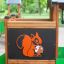 Forest Treehouse playhouse with slide présentant des panneaux en bois et une décoration d’écureuil sur une aire de jeu