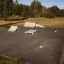 Skatepark avec Curb Horizontal rampes et obstacles installés sur une surface en asphalte.