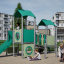 Tower playhouse with a slide sur une aire de jeux avec des enfants jouant autour