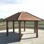 Gazebo extérieur en bois Firehouse avec structure de toit à lattes sur une base en gravier.