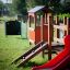 Équipement de aire de jeux pour enfants avec toboggan rouge et structure d’escalade en bois.