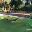 Balançoire hamac verte pour enfants installée sur de l’herbe artificielle.