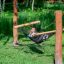 Enfant se relaxant dans un hamac en filet noir entre des poteaux en bois dans un parc verdoyant
