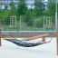 Hammock avec cadre en bois et filet noir sur l’aire de jeux.