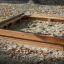 Sandpit en bois rempli de sable dans une aire de jeux entourée de feuilles d’automne.