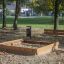 Sandpit en bois en extérieur dans un parc avec un banc à proximité