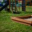Sandpit en bois dans une aire de jeux avec toboggan et structure d’escalade