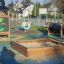 Sandpit en bois dans une aire de jeux extérieure colorée.
