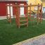 Chimpanzee wooden playhouse avec échelles d'escalade et barres sur gazon artificiel vert.