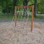 V-shape Net wooden playhouse dans une aire de jeux sablonneuse entourée d’arbres.