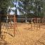 V-shape Net wooden playhouse dans une aire de jeux avec des filets d’escalade et un sol en copeaux de bois.
