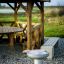 Gril extérieur à côté d'un gazebo en bois avec banc et table de pique-nique.