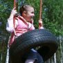 Une fille en train de balancer sur la balançoire  en bois avec le siège Pneu Double