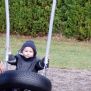 Un enfant en train de  jouer sur la balançoire  en bois avec le siège Pneu