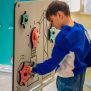 Enfant jouant avec le panneau interactif Sensory Box, équipé d'engrenages colorés et de boutons à ma